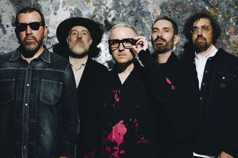 Electronic pop band Hot Chip posing together against a textured wall background.